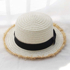 Close-up of white boater straw hat with black bow and fringed brim for summer vacation