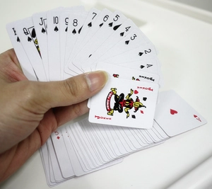 Macro shot of hand holding fan of mini playing cards including Joker and classic suits