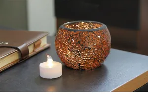 Detail of amber mosaic glass candle holder with LED tea light on a wooden surface