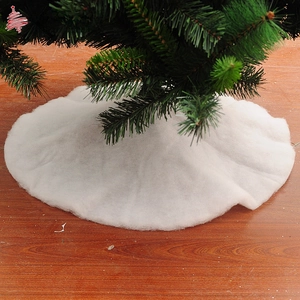 Detailed view of white faux fur Christmas tree skirt with plush snow effect on wood floor