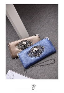 Detail of metallic crinkle leather skull wallets in blue and bronze with ornate metal corners