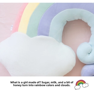 Close-up of a plush rainbow and cloud pillow with soft macaron stripes and a sewn-in label