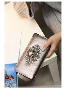 Close-up of silver skull long wallet with metallic baroque patterns and punk studs