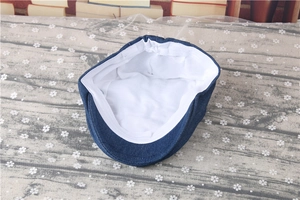 Detailed view of dark blue denim baby beret with breathable white lining and elastic edge