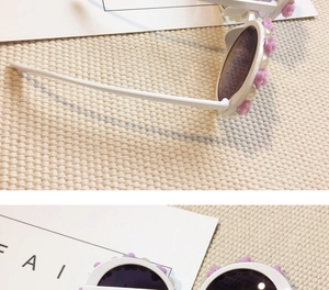 Detail of white round frame children sunglasses with purple flowers and pearls decoration