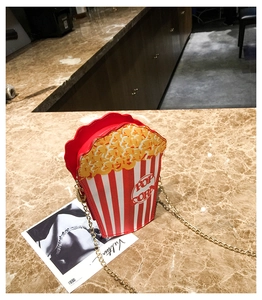 Detail view of popcorn-shaped crossbody bag with gold chain on marble surface