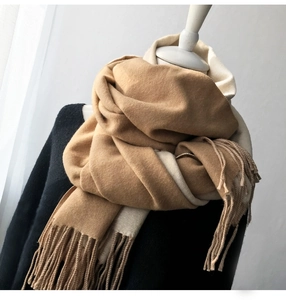 Detail of camel and beige double-sided scarf showing thick cashmere-like texture and tassels