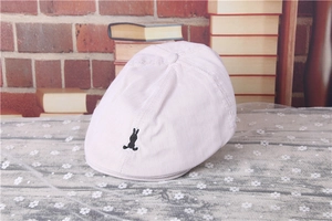 Detail of baby striped beret featuring a black rabbit embroidery on light brown fabric