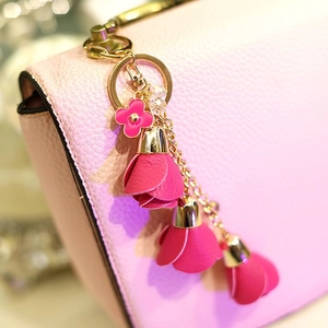Detail of floral leather keychain with gold hardware on pink textured handbag
