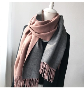 Detailed close-up of soft pink and gray double-sided scarf with thick fringe tassels