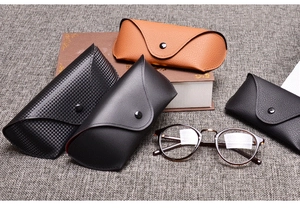 Detail view of four textured leather sunglass cases and vintage round frame glasses