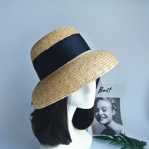 Detail of hand-woven straw sun hat with black ribbon and elegant French vintage texture