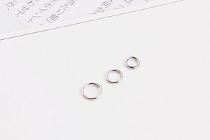 Close-up of three silver-plated jump rings in different sizes for jewelry making DIY