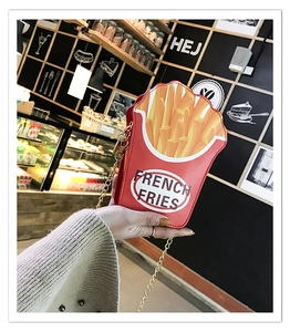 Close-up of a creative french fries crossbody bag with golden chain in hand