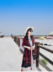 Detail of bohemian floral shawl featuring red tassels and lightweight fabric in sea breeze