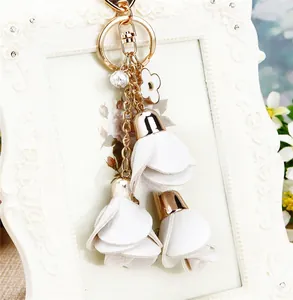 Detailed view of elegant white floral keychain with gold metal ring on vintage frame
