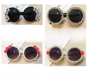 Detail view of round frame kids sunglasses featuring daisy and floral 3D decorations