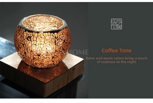 Detail of mosaic glass candle holder with warm amber glow and crackle texture