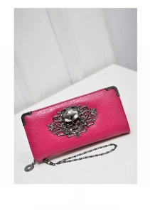 Macro detail of pink leather long wallet with silver skull and floral metal emblem