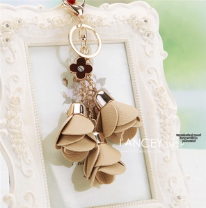 Detail of floral car keychain with leather flower petals and clover charm on gold ring