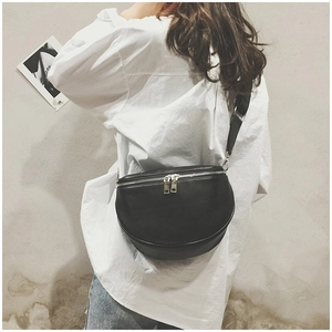 Minimalist black leather half-moon crossbody bag shown on a model against a white shirt