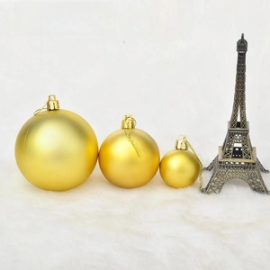Three sizes of matte gold Christmas ornaments arranged on a white soft faux fur rug