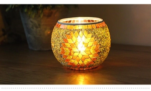 Detailed view of mosaic glass candle holder with amber sunburst pattern and warm glow