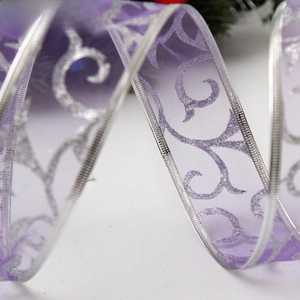 Macro view of purple translucent Christmas ribbon with silver glitter scrollwork patterns