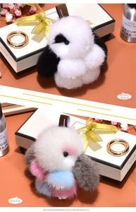 Macro detail of fluffy rabbit pendants in white-black and multicolor with gold metal clips