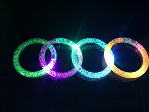 Detailed macro view of four colorful LED glowing acrylic bubble bracelets in dark background