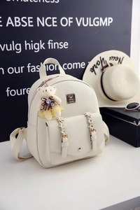Detailansicht des weißen PU-Rucksacks mit Lychee-Struktur und süßem Bären-Anhänger