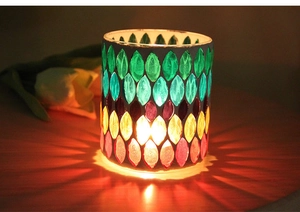 Macro shot of mosaic glass candle holder casting warm radial light patterns on wood