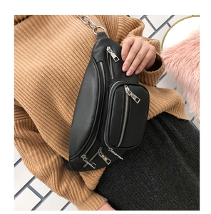 Detail of black faux leather waist bag featuring multiple zippers and a metal chain strap