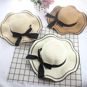 Detail of wide-brim wavy straw hats with black ribbons in beige and khaki shades