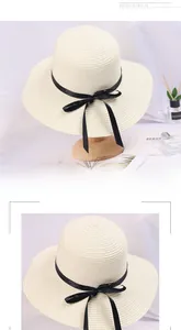 Detail of a chic cream straw sun hat featuring an elegant black ribbon and bow detail