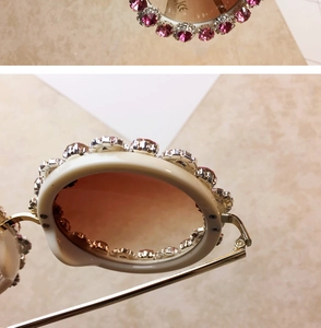 Detail of white sunglasses with pink heart crystals and gold metal temples