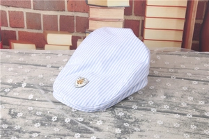 Close-up of blue striped baby beret featuring a golden anchor shield emblem detail