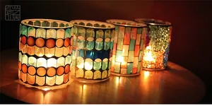 Macro shot of four handmade mosaic glass candle holders on a wooden table with warm light