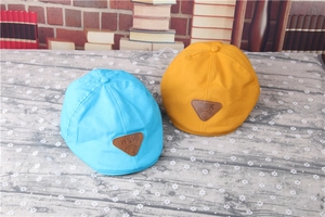 Detail of light blue and mustard yellow striped baby berets on a floral surface