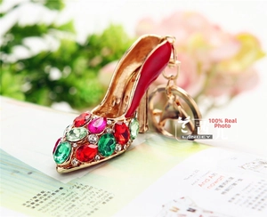 Close-up of golden high heel keychain with vibrant multicolored rhinestones on red lacquer