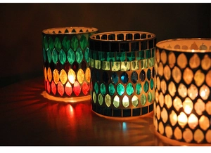 Detailed view of three mosaic glass candle holders with vibrant colorful light patterns