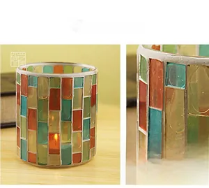 Detail of mosaic glass candle holder with blue, green, and orange tiles on wood