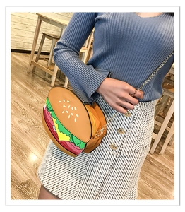 Detail of creative hamburger shaped crossbody bag with gold chain strap on model