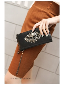 Detail of black punk wallet featuring silver skull relief and textured leather surface