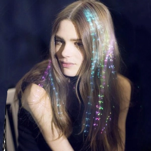 Close-up of colorful LED fiber optic hair extension glowing in dark party atmosphere