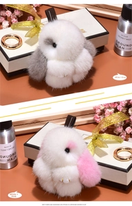 Detail of plush bunny keychains in white-grey and white-pink with golden rings