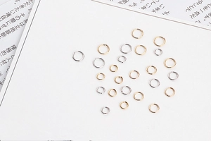 Detailed view of various sizes of gold and silver open jump rings for jewelry making