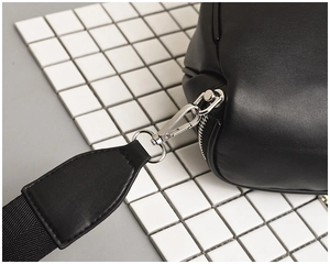 Close-up of the silver metal buckle and nylon strap on a minimalist black crossbody bag