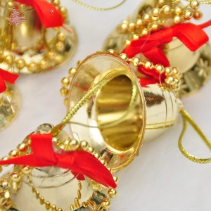 Macro shot of gold Christmas bell with red bow and engraved snowflake details