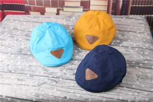 Close-up of baby striped beret hats in blue, yellow, and navy with leather patches